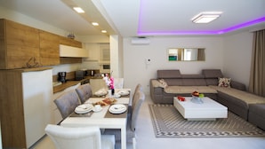 A modern living room with a dining area, a sofa set, and a coffee table with a vase of flowers. - Apartments Leone (Baska Voda)