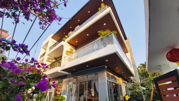 Un edificio moderno de dos pisos con balcones, ventanas amplias y mobiliario exterior.