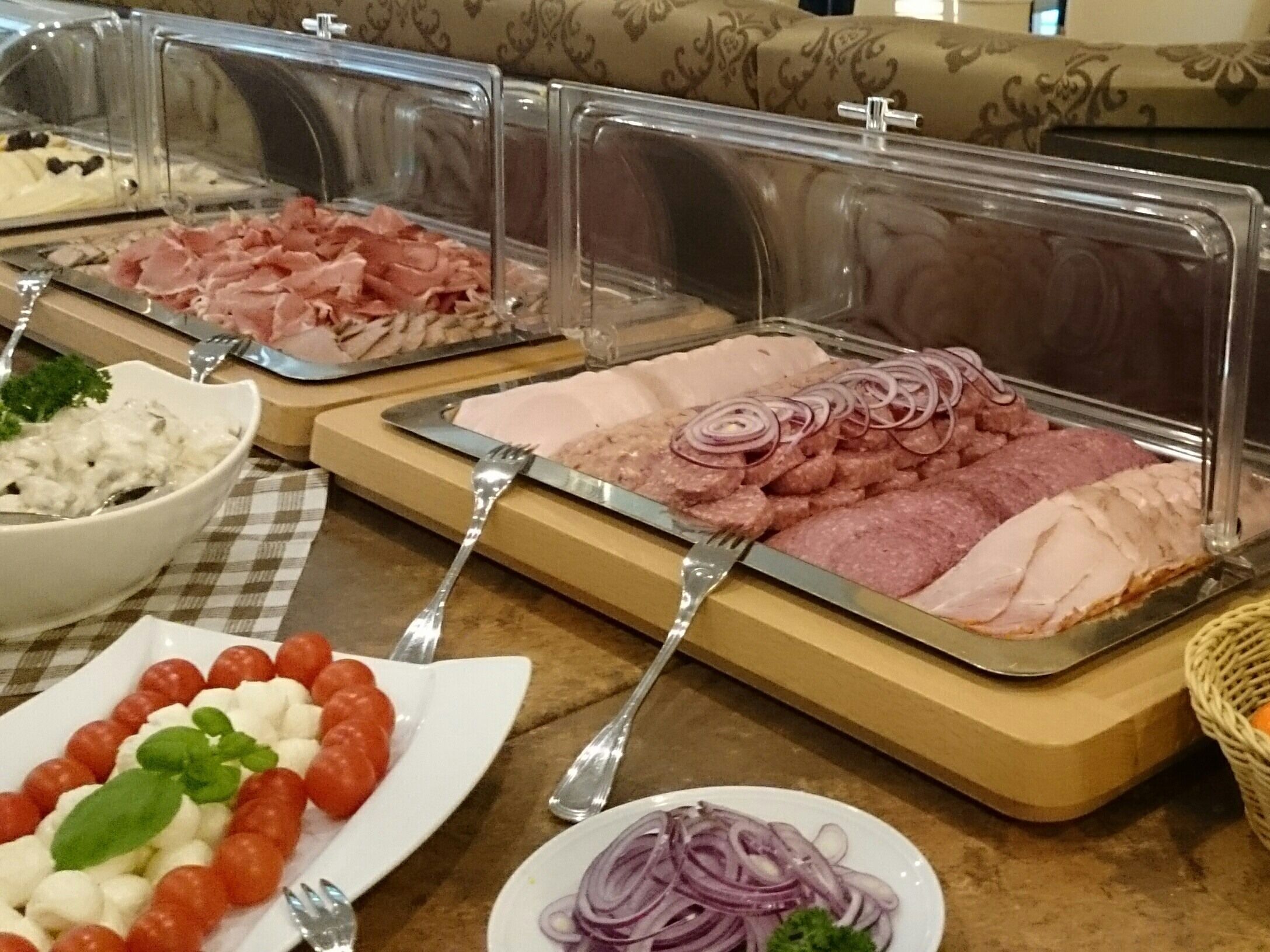 A buffet with various food options including sliced meats, cheeses, and garnishes.