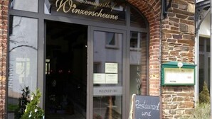 En restaurang med en skylt där det står ”Restaurang och vinkällare öppet” framför en byggnad av tegel.