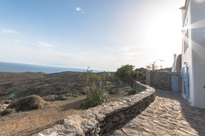 A stone-walled building with a view of the sea and distant hills.