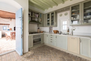 Functional kitchen with central island, sink, stove, and range hood, equipped with a coffee maker and kettle.