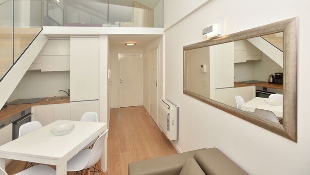 Eine moderne Wohnung mit Essbereich, Küche und einem großen Spiegel, der den Raum widerspiegelt.
