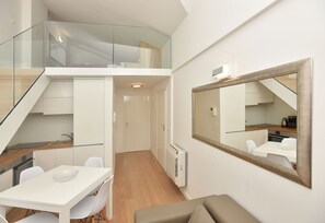 Eine moderne Wohnung mit Essbereich, Küche und einem großen Spiegel, der den Raum widerspiegelt.