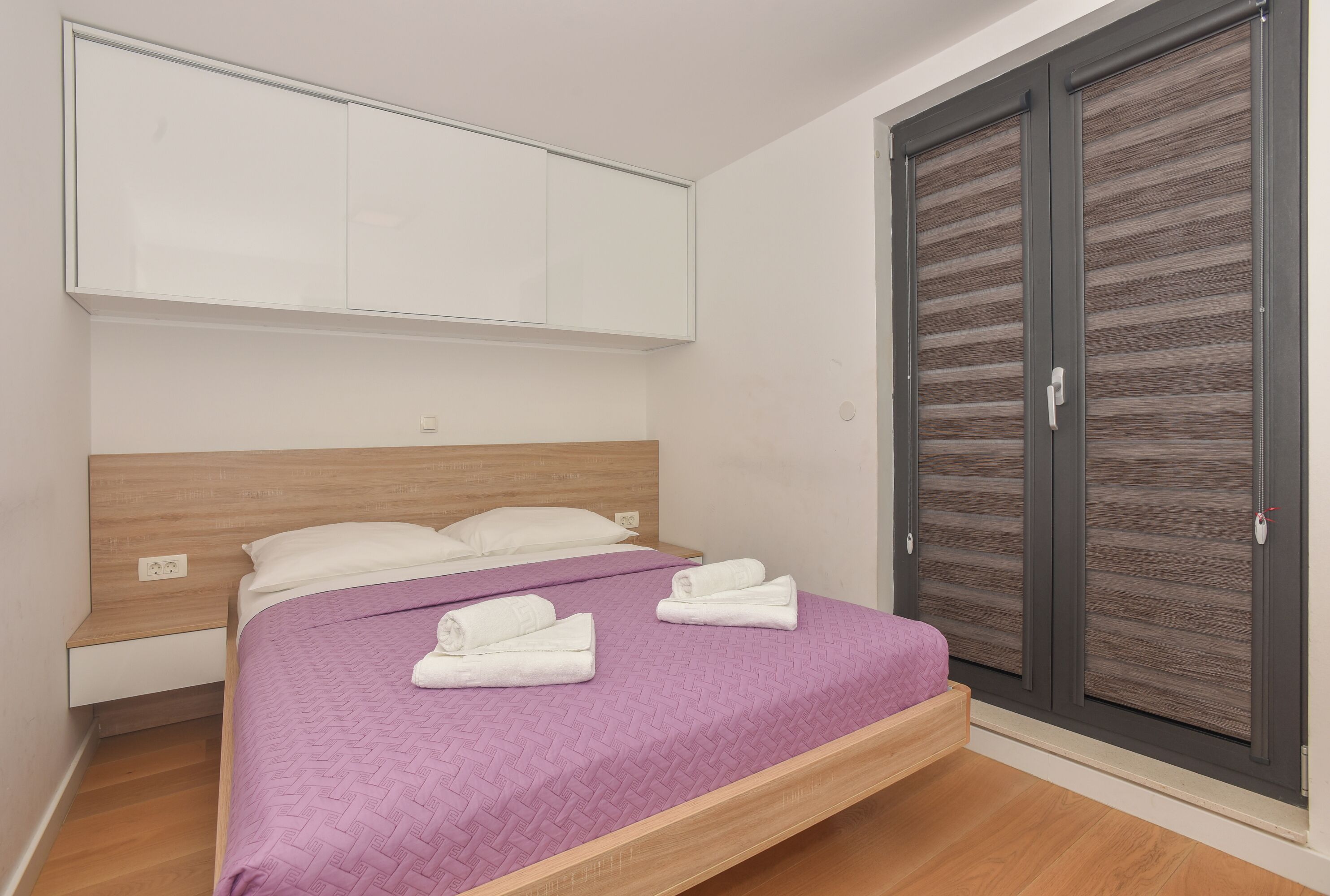 A bedroom with a bed, a wardrobe, and a nightstand.