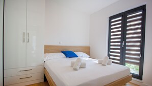 Ein Schlafzimmer mit Bett, Kleiderschrank und einem Fenster mit Jalousien.
