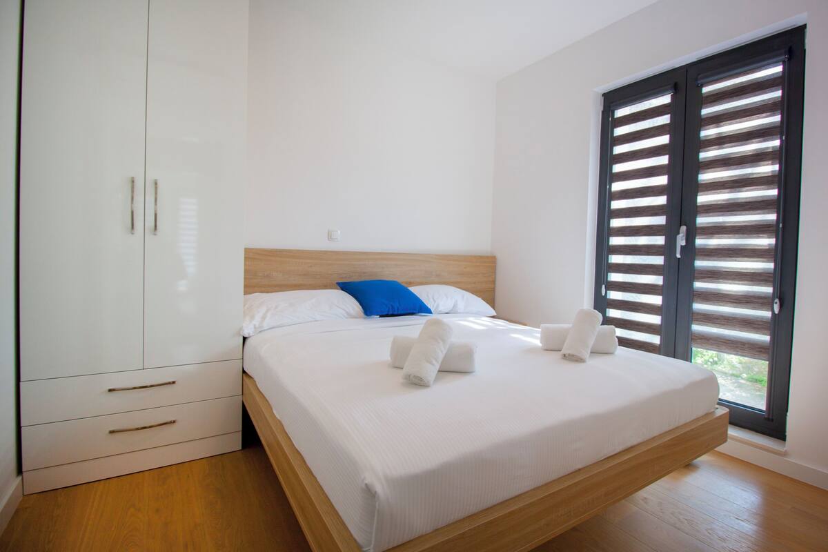Een slaapkamer met een bed, een kledingkast en een raam met zonwering.