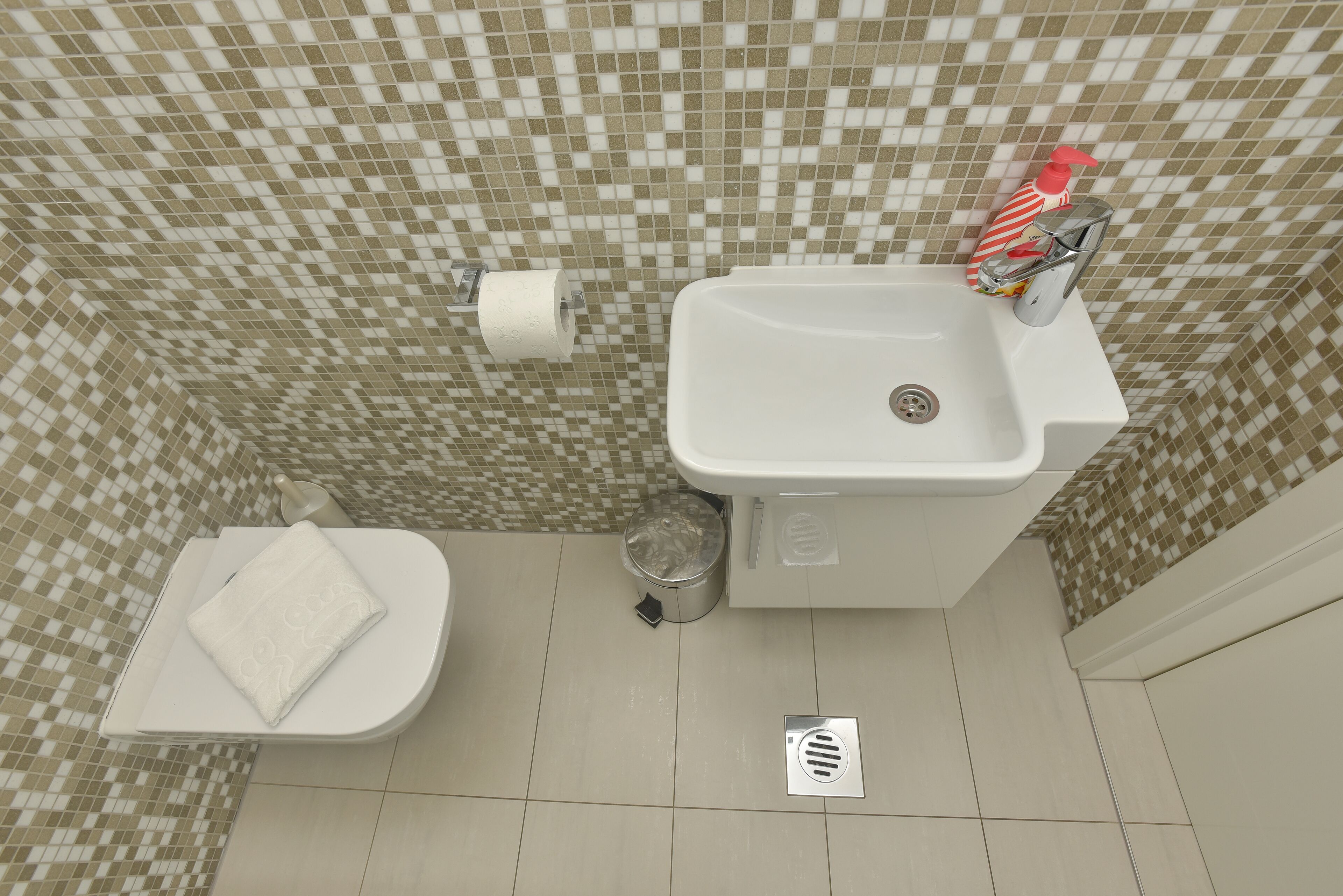 Een badkamer met toilet, wastafel en betegelde wanden.