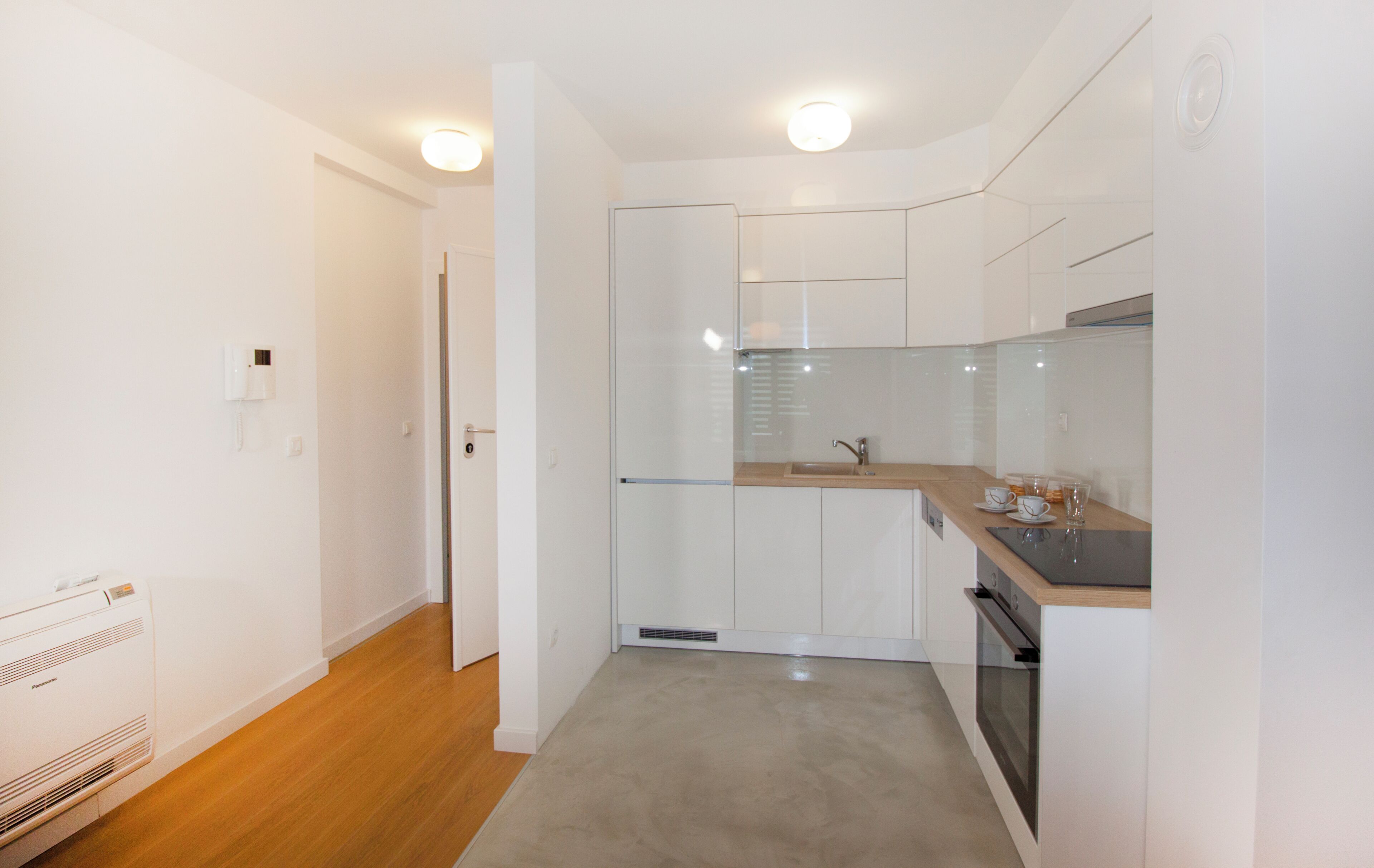 A modern kitchen with white cabinets, a wooden countertop, and a built-in oven.