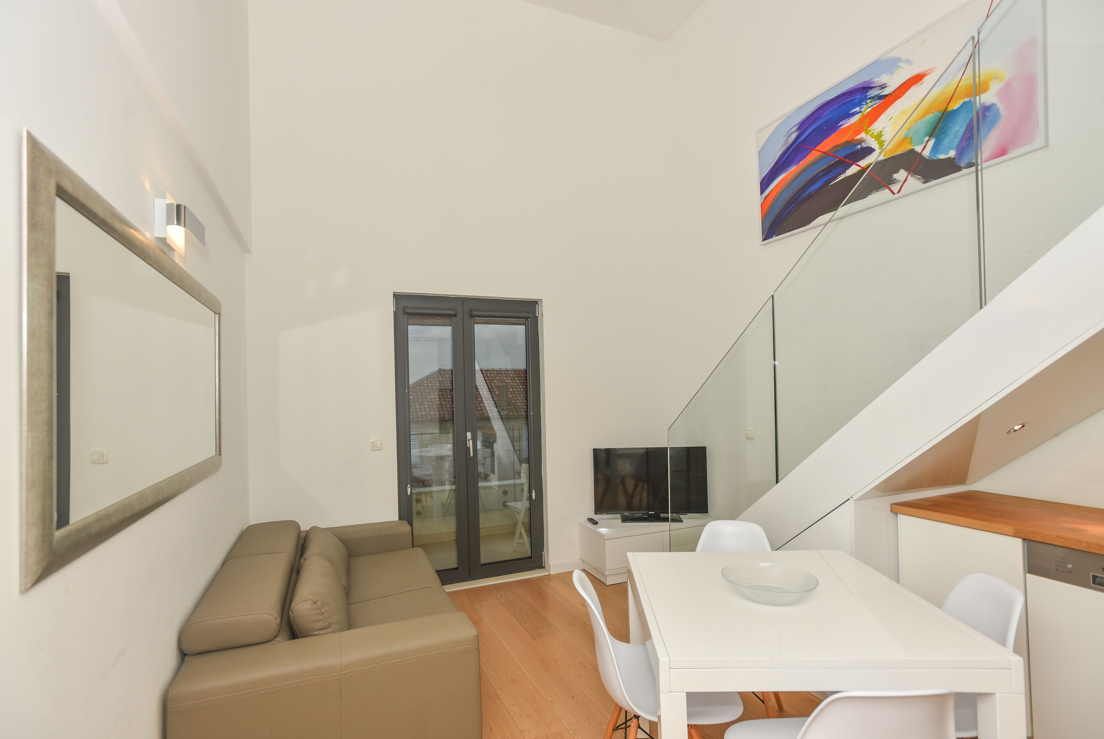 A modern living room with a sofa, a dining table, and a TV.