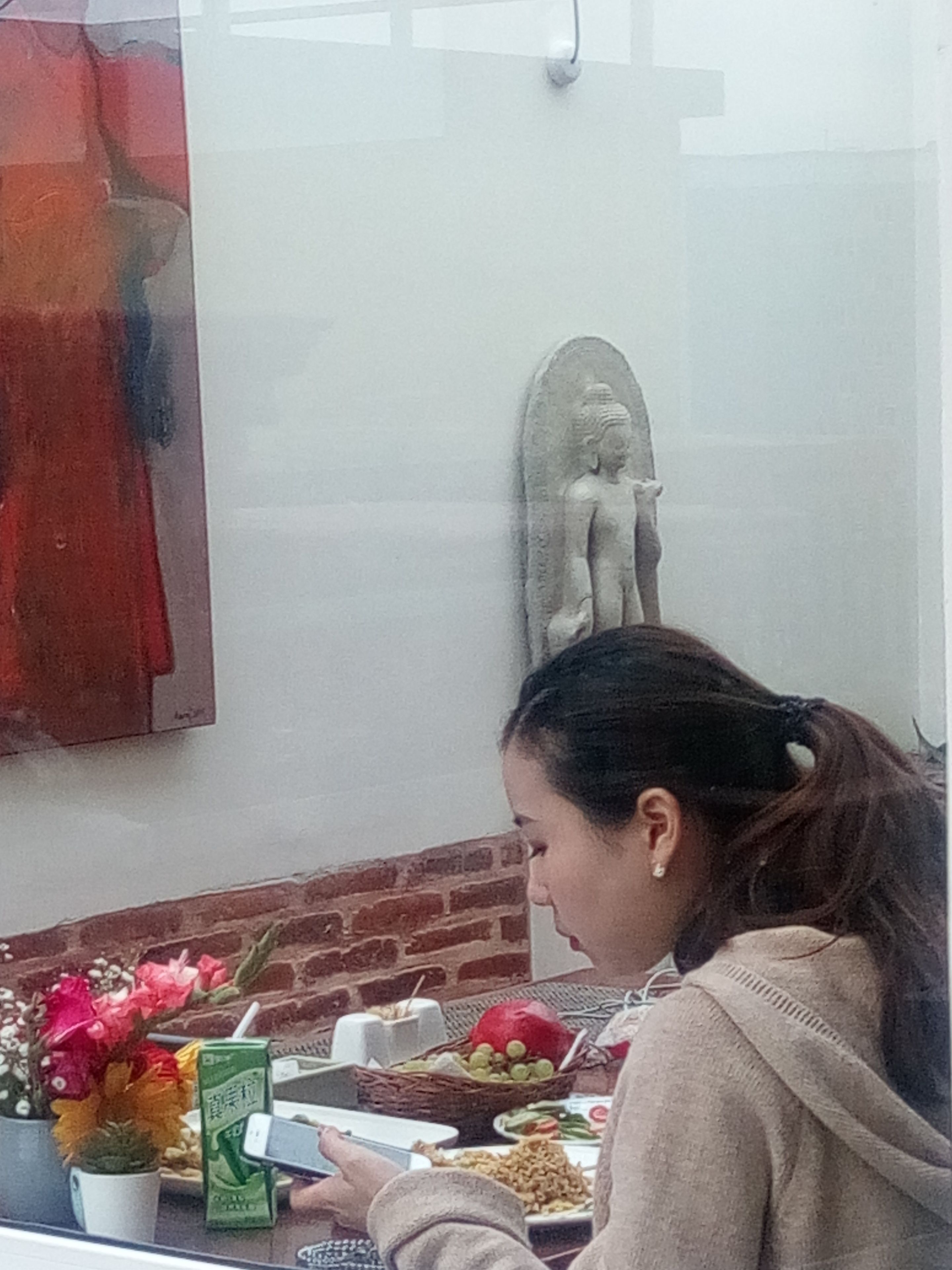 A dining area with a table set for a meal, a decorative statue, and a wall with a red abstract painting.