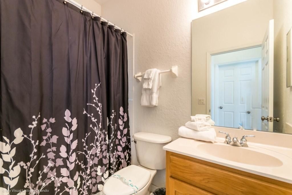 A bathroom with a toilet, a sink, a mirror, and a shower curtain with a floral pattern.