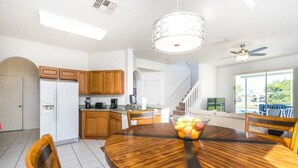 A modern kitchen with wooden cabinets, a white refrigerator, and a dining area with a round wooden table and chairs.