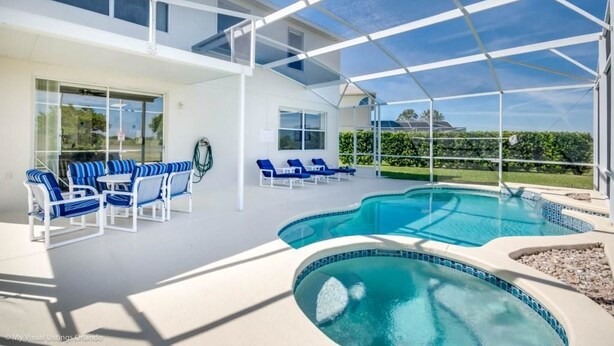 A modern outdoor pool area with lounge chairs and a glass-enclosed patio.