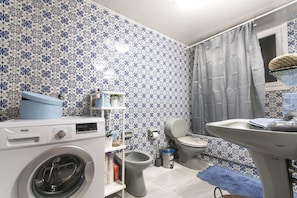 A bathroom with a washing machine, toilet, bidet, and sink.