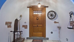 Una porta de fusta amb una reixa de metall, un sòl de pedra i una balança penjant.