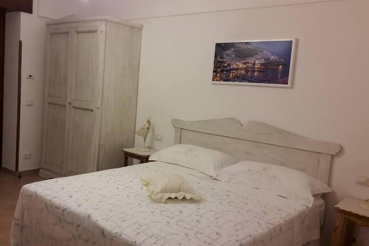 Ein Schlafzimmer mit Bett, Kleiderschrank, Stuhl und einem Bild an der Wand.