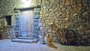 Edifici de pedra amb una porta de fusta i una roda gran.