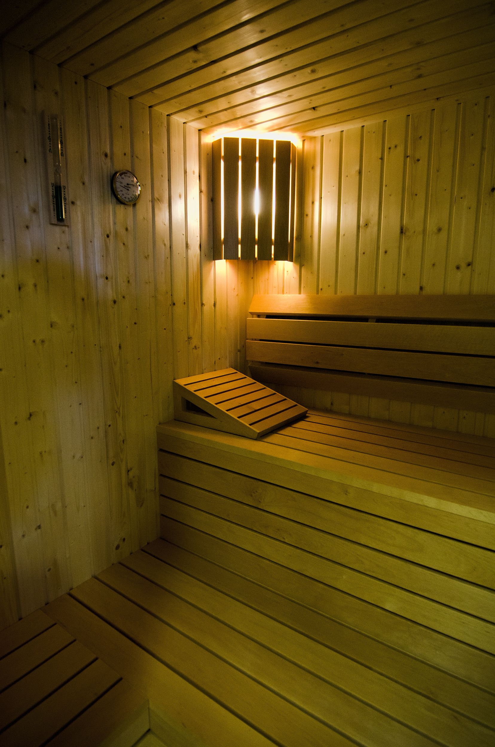 A wooden sauna with benches and a wall-mounted clock.