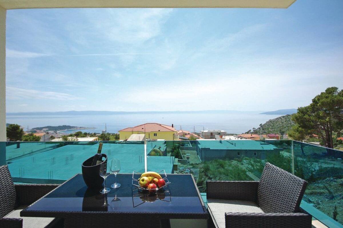 Un balcon avec une table, un verre de vin et un panier de fruits.