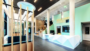 A modern hotel lobby with a reception desk, seating area, and a staircase leading to upper floors. - Yugo Explore - Ardcairn House (Dublin)