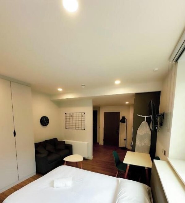 A hotel room with a bed, a small table, a chair, a sofa, a wardrobe, and a mirror. - Yugo Explore - Ardcairn House (Dublin)
