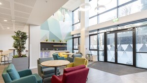 A modern indoor space with a round table, colorful chairs, and a potted plant. - Yugo Explore - Ardcairn House (Dublin)