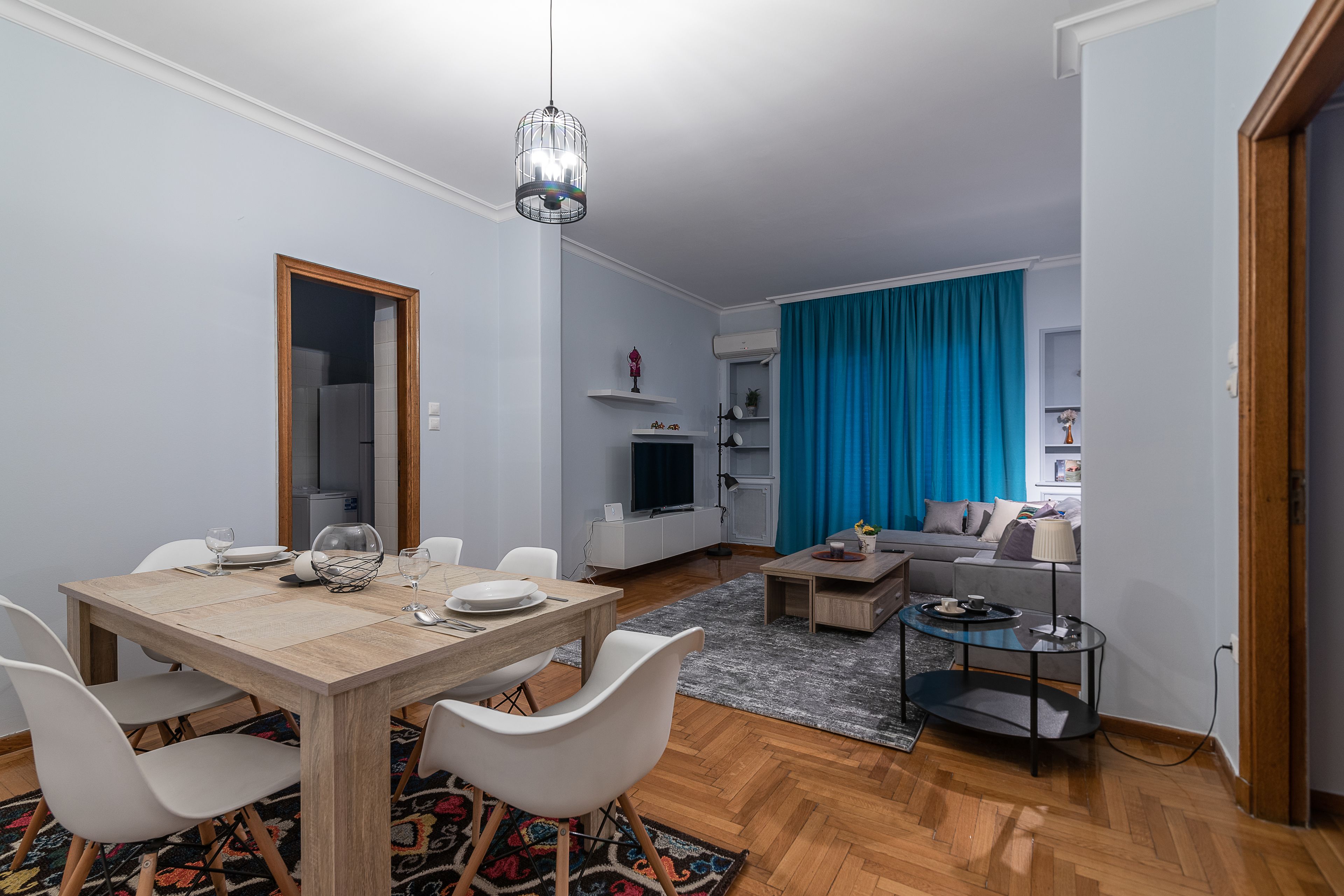 A modern living room with a dining area, a TV, and a sofa.
