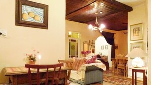 A cozy living room with a wooden dining table, chairs, a sofa, and a patterned rug. - Cosy 6 Person Cottage With Mountain View (Barrydale)