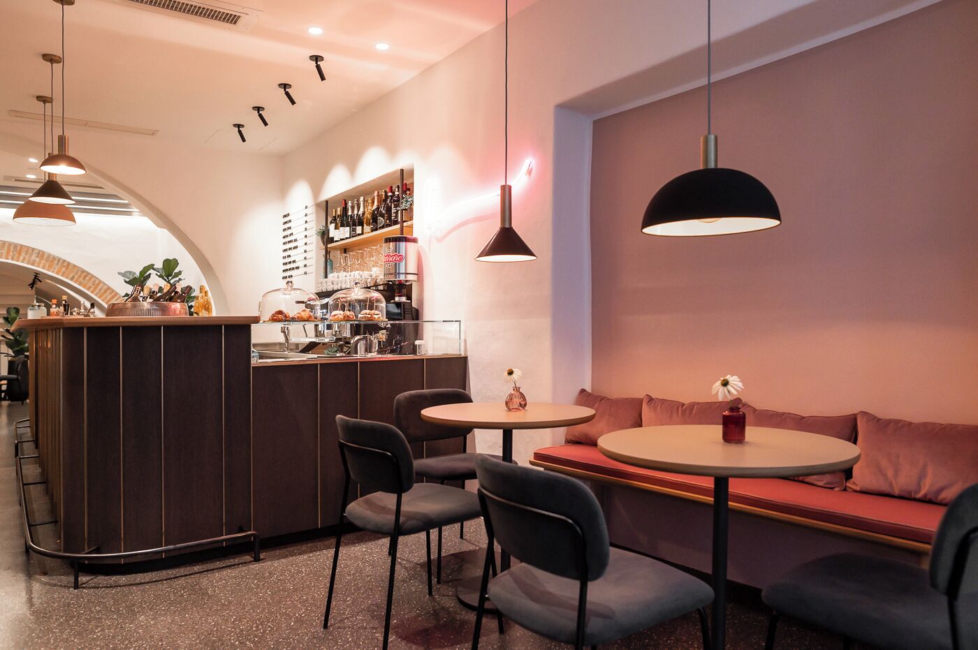 A modern bar area with a counter, seating, and pendant lighting.
