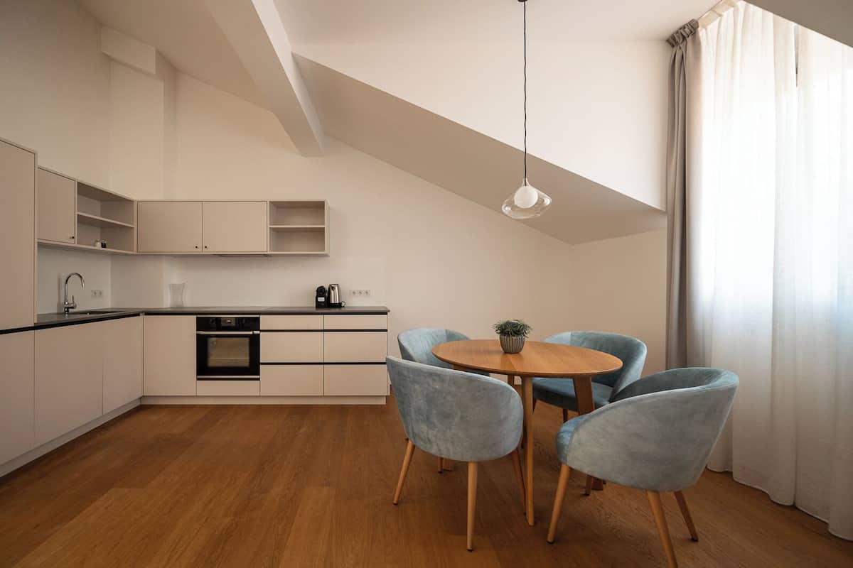A modern kitchen with a dining area, featuring a round wooden table and four blue chairs.