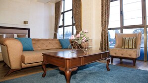 Una sala de estar con sofá, sillón, mesa de centro y ventanas amplias.