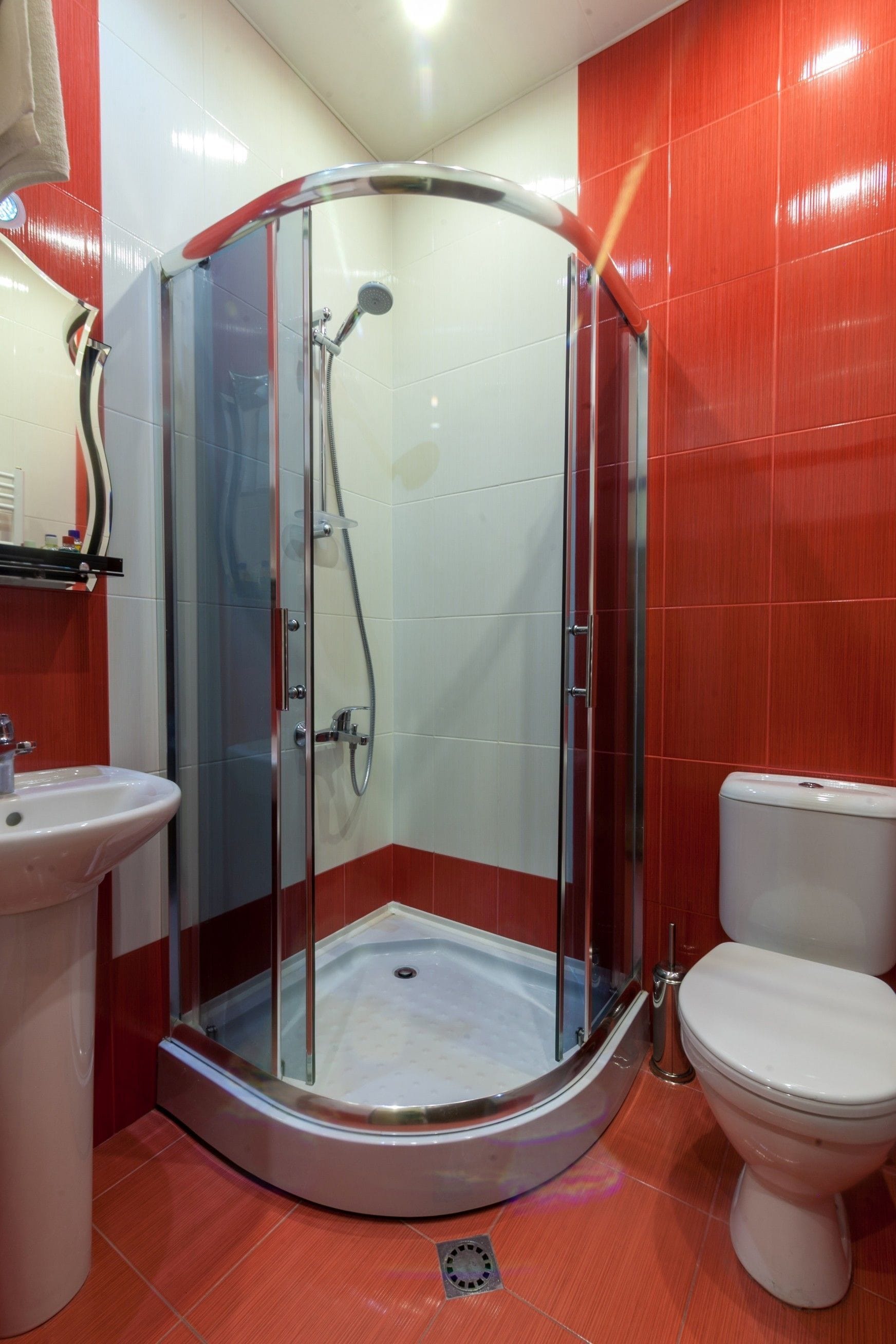 A bathroom with a glass-enclosed shower, a white sink, and a toilet.