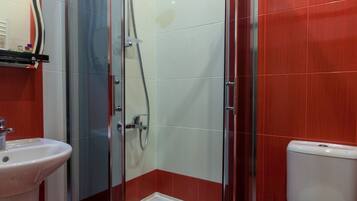 A bathroom with a glass-enclosed shower, a white sink, and a toilet.