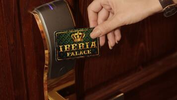 Una mano preme un campanello con un cartello che riporta la scritta 'Iberia Palace'.