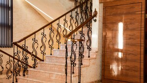 Una escalera con barandales de metal negro ornamentados y una puerta de madera con diseño tallado.