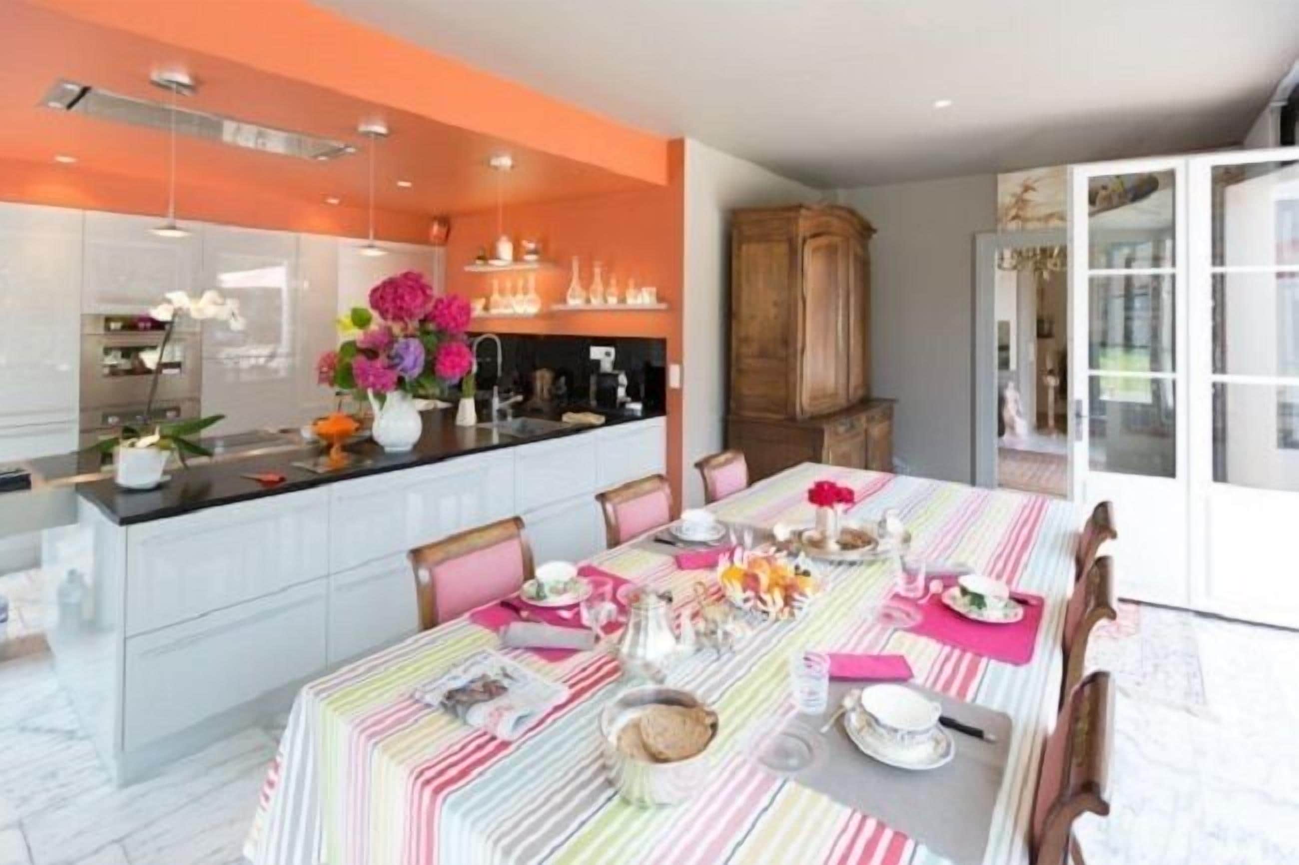 Une cuisine moderne dotée d’un grand îlot central, d’un coin repas avec une nappe à rayures et d’un meuble en bois.