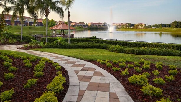 A landscaped pathway leading to a gazebo by a lake with a fountain, surrounded by well-maintained grass and shrubs. - Encantada Resort 8549 (Kissimmee)