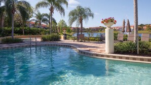 A swimming pool with a curved edge, surrounded by palm trees and lounge chairs. - Encantada Resort 8549 (Kissimmee)