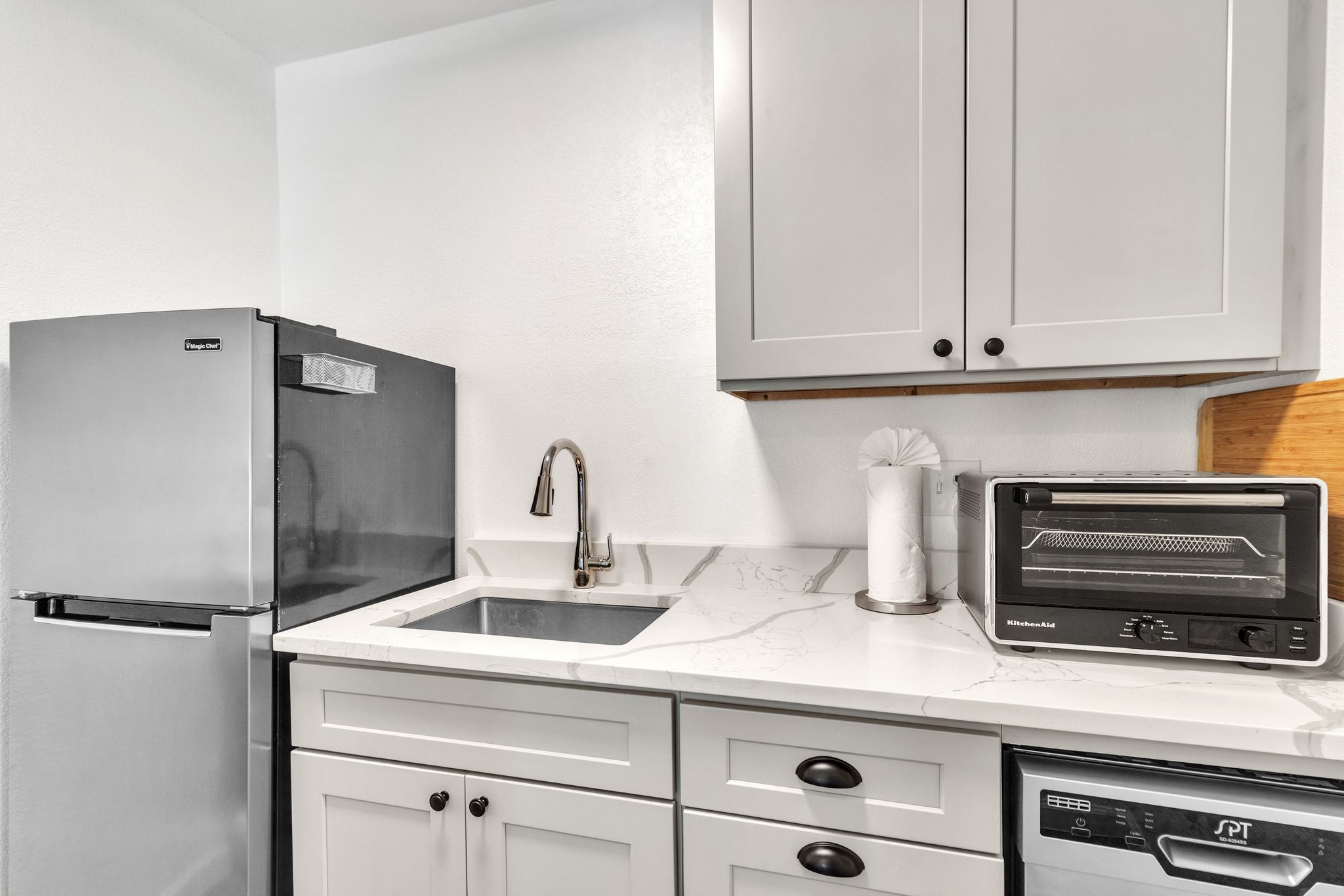 A kitchen with a refrigerator, sink, microwave, and dishwasher.