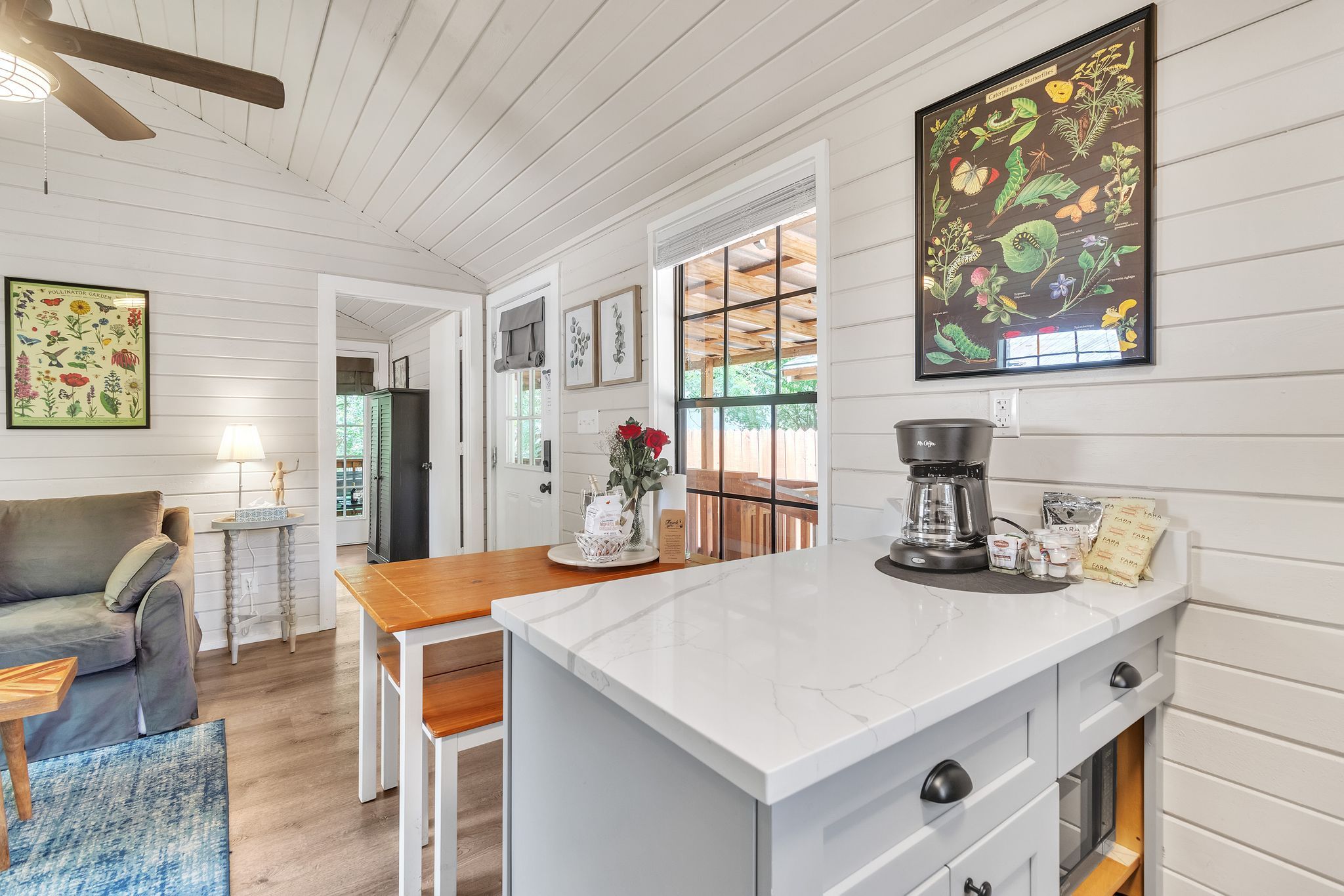 A modern kitchen with white cabinetry, a marble countertop, and a coffee maker.