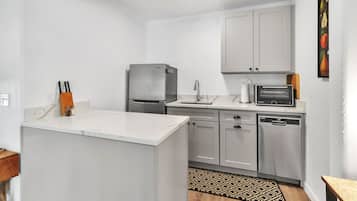 A compact kitchen with a refrigerator, microwave, sink, and dishwasher.