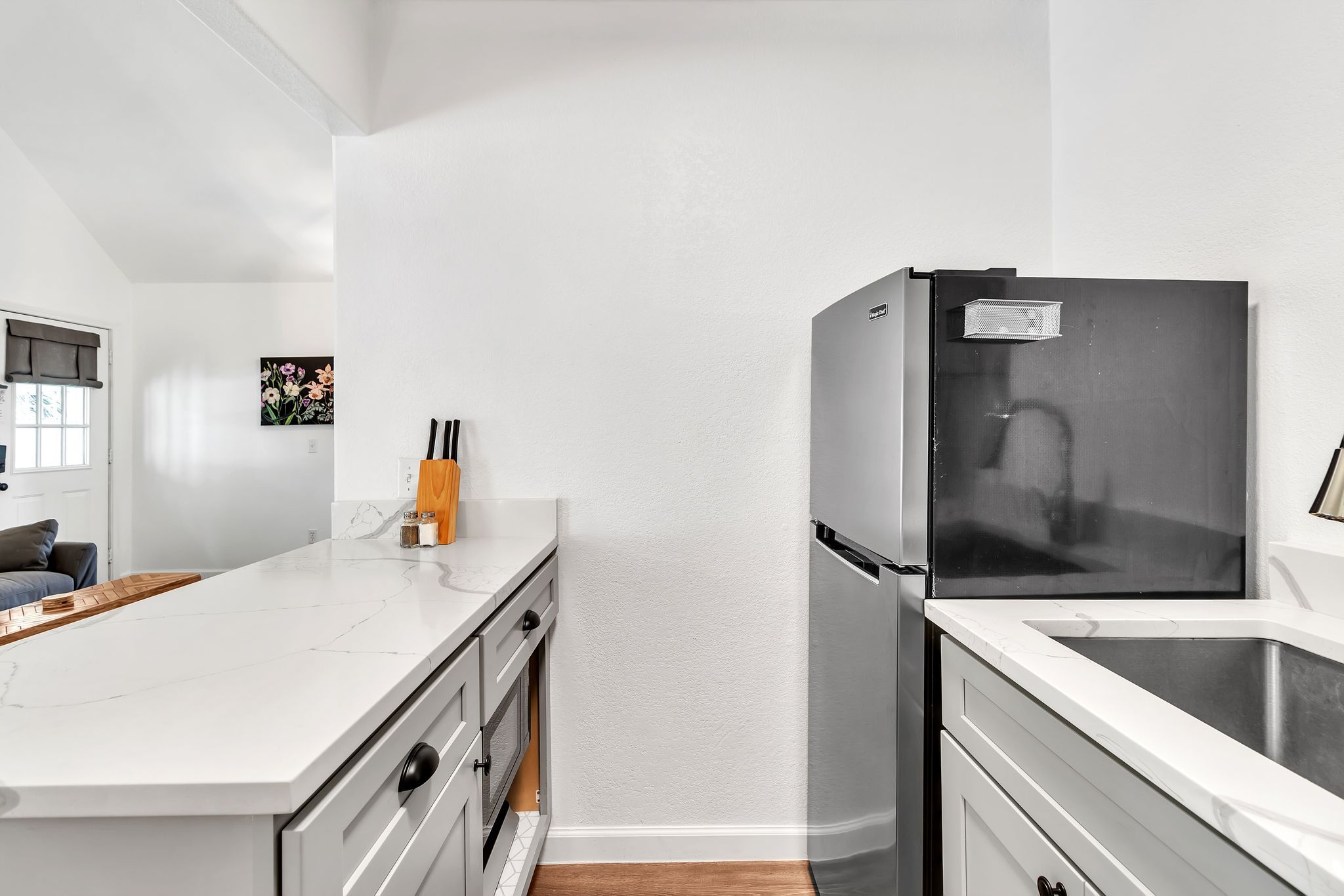 Una cocina moderna con armarios blancos, un refrigerador de acero inoxidable y una encimera de madera.