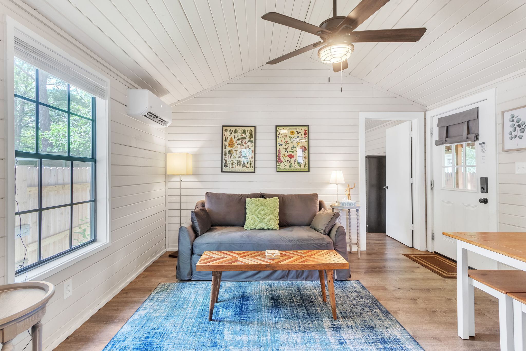 A cozy living room with a sofa, a coffee table, and a ceiling fan.