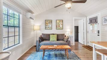 A cozy living room with a sofa, a coffee table, and a ceiling fan.
