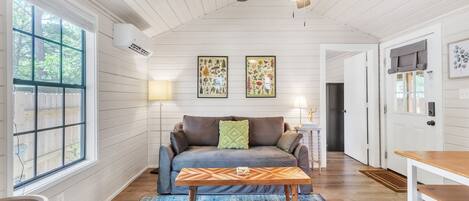 A cozy living room with a sofa, a coffee table, and a ceiling fan.