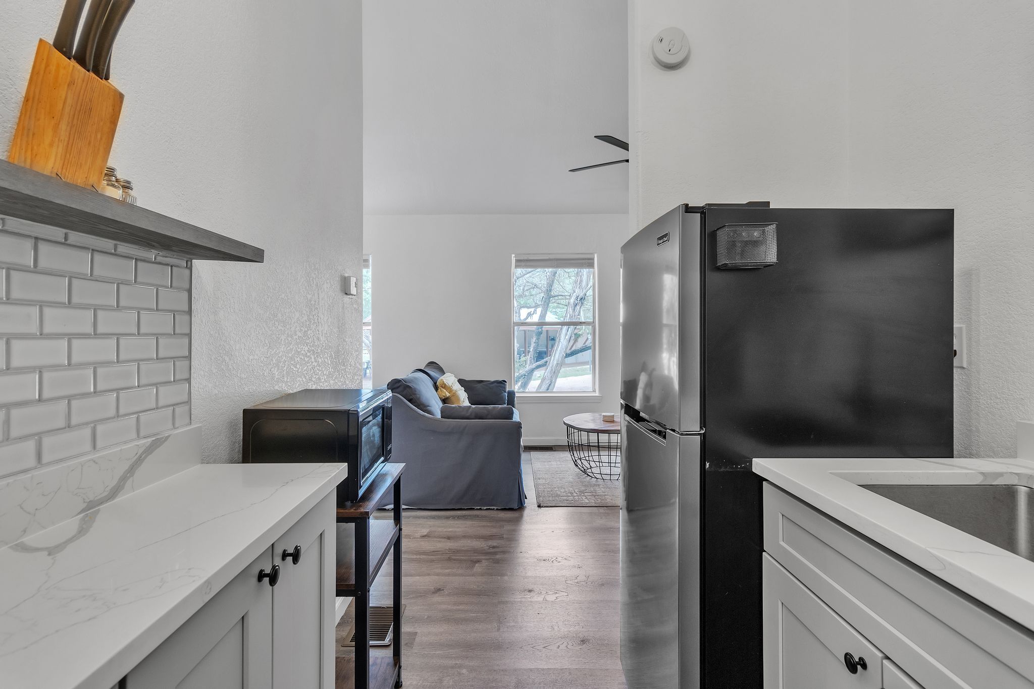 Una cocina moderna con refrigerador empotrado, una zona de comedor con sofá y un ventanal que proporciona luz natural.