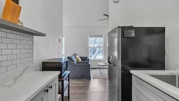 Una cocina moderna con refrigerador empotrado, una zona de comedor con sofá y un ventanal que proporciona luz natural.