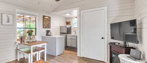 Un espacio habitable compacto con comedor, kitchenette y televisor.