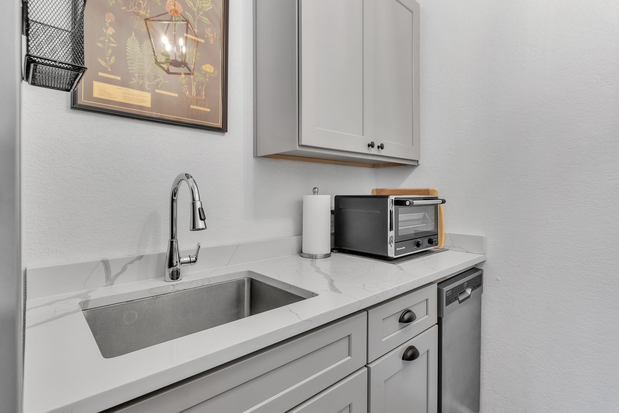 Eine Küche mit doppelter Spüle, einem modernen Wasserhahn, einem Toaster und einem Geschirrspüler.
